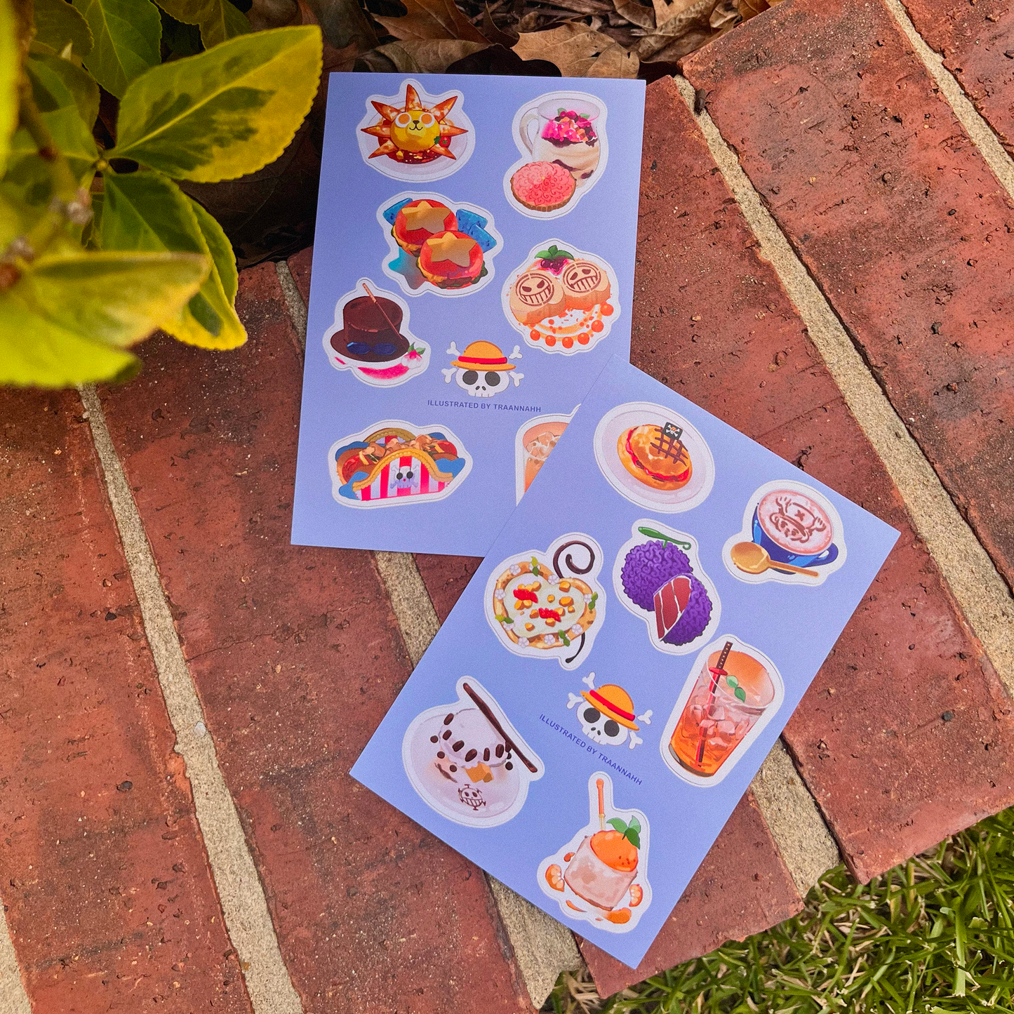 Two sheets of colorful stickers on a brick surface with plants in the background